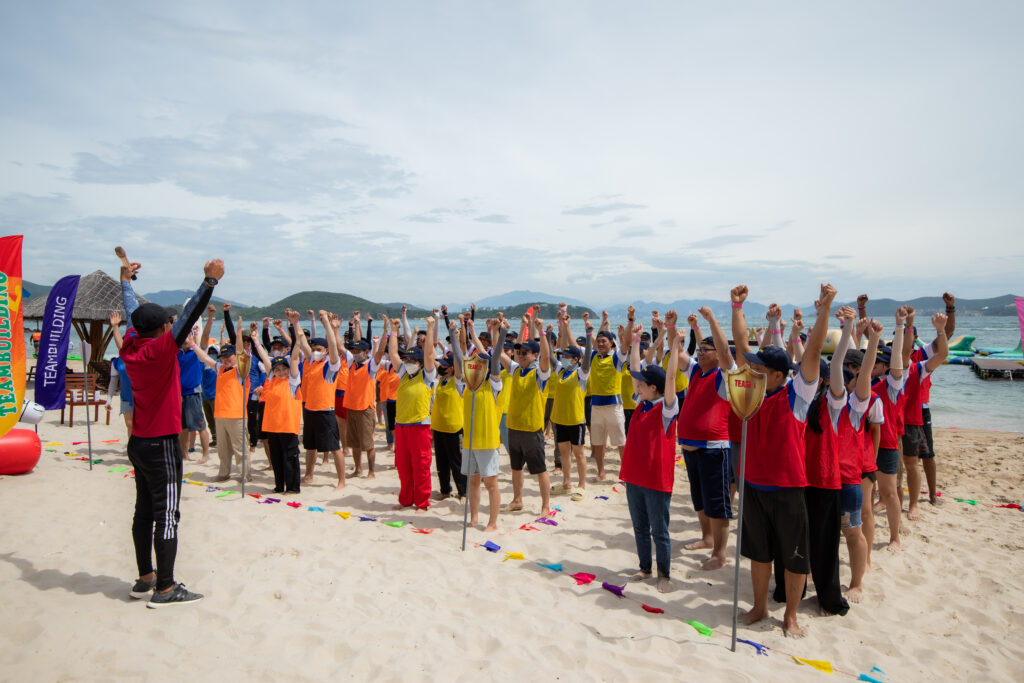 MC team building đang dẫn chương trình teambuilding cho các đội chơi trên bãi biển.