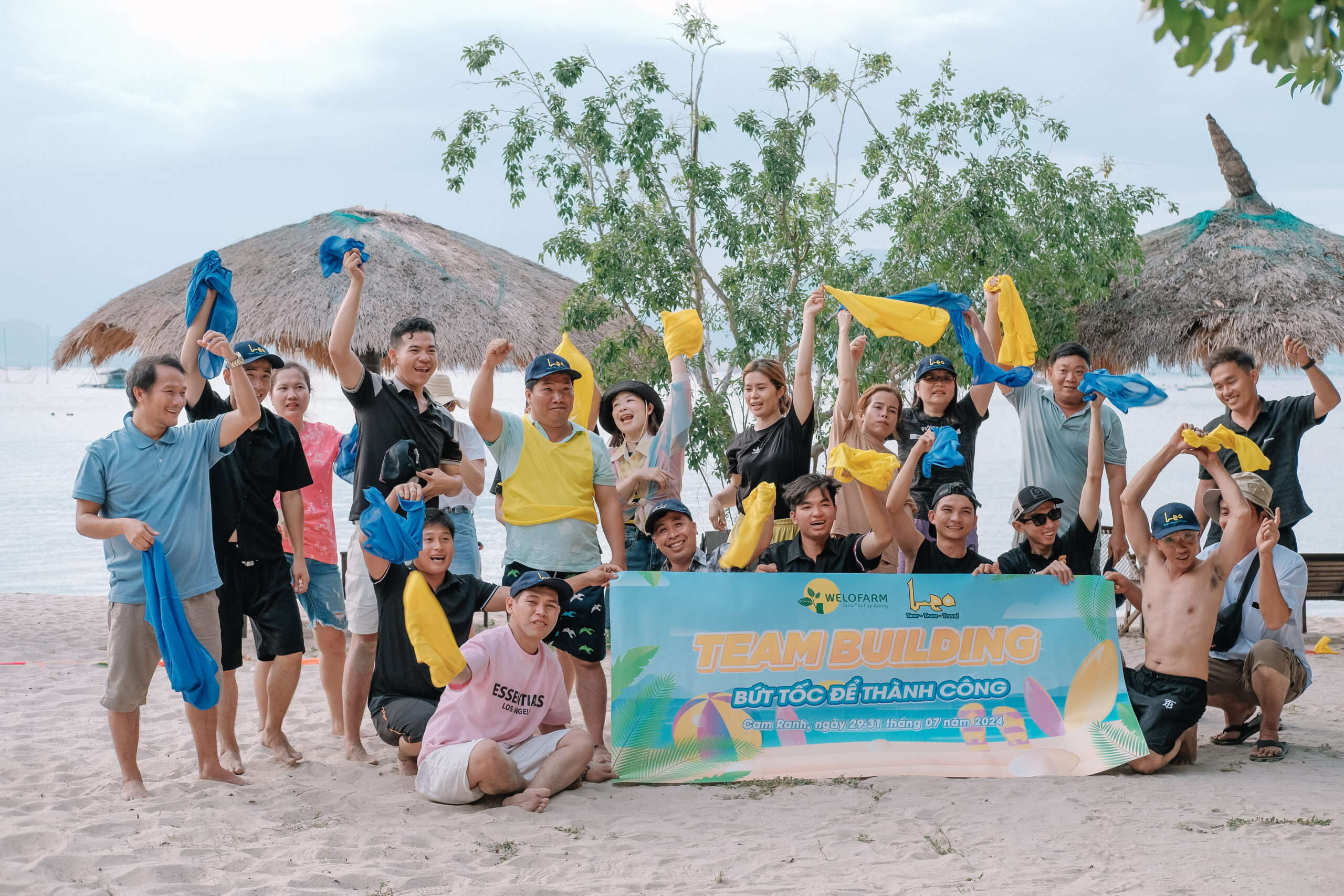 Nhóm nhân viên tham gia hoạt động team building ngoài trời, cùng giơ cao khăn đồng phục và thể hiện tinh thần gắn kết, vừa tạo trải nghiệm vui vẻ vừa hỗ trợ doanh nghiệp tối ưu chi phí team building.