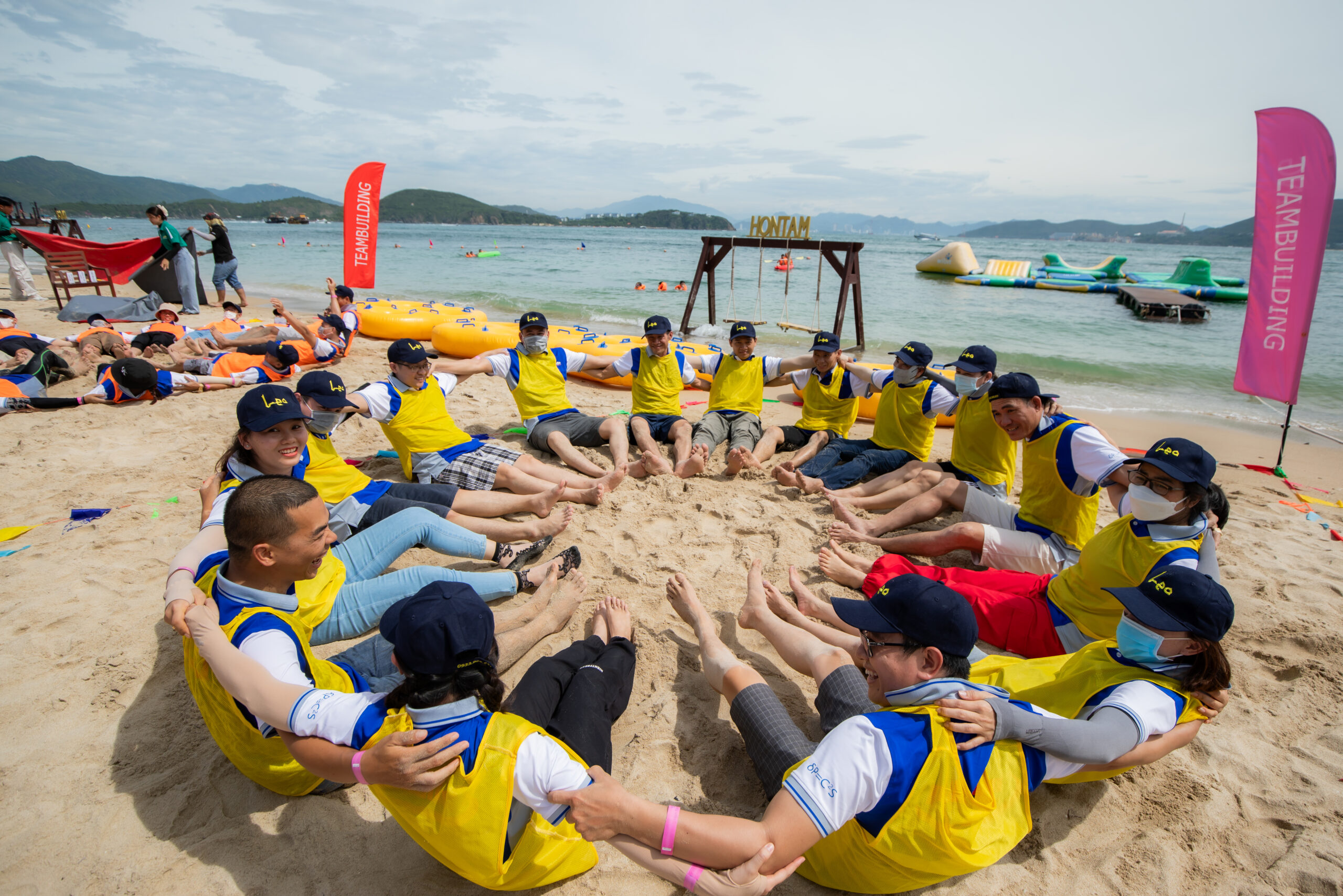 Khách mặc áo đồng phục vàng chơi team building kết nối tại bãi biển.
