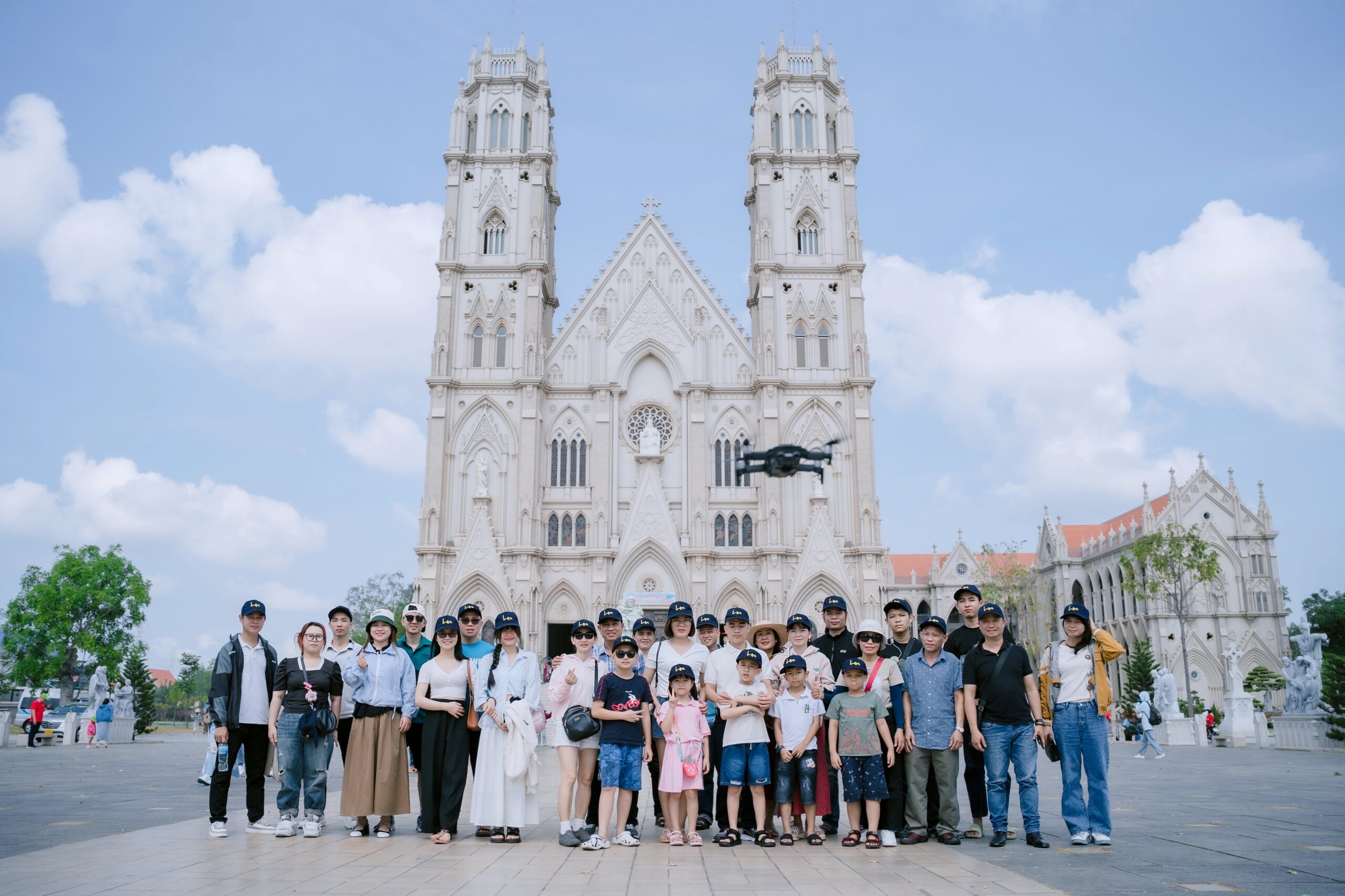 alt = "Đoàn khách trong tour nghỉ dưỡng gia đình tham quan nhà thờ phong cách châu Âu, lưu giữ khoảnh khắc kết nối giữa các thế hệ."