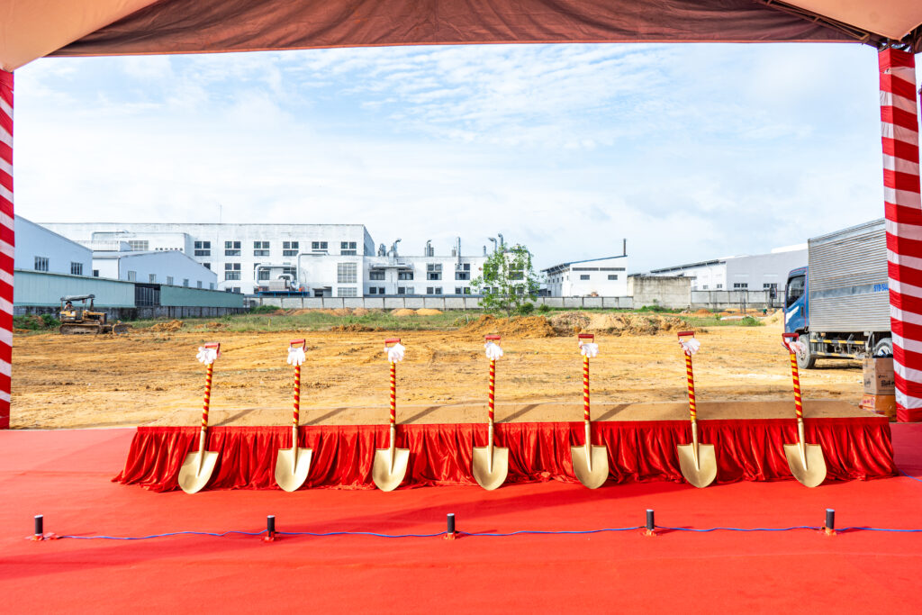 Sân khấu tổ chức lễ khởi công với hàng xẻng vàng trang trí ruy băng đỏ, nền đất công trình