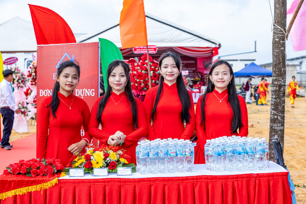 Lễ tân mặc áo dài đỏ rạng rỡ đón khách tại sự kiện do đơn vị tổ chức lễ khánh thành uy tín – công ty sự kiện miền Nam thực hiện.