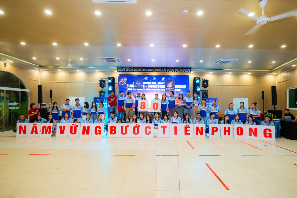 alt=Sự kiện Workshop trải nghiệm doanh nghiệp đã thành công, các thành viên cùng nhau chụp ảnh với khẩu hiệu "NĂM VỮNG BƯỚC TIÊN PHONG" và tấm biển "8.0", đánh dấu một cột mốc quan trọng.